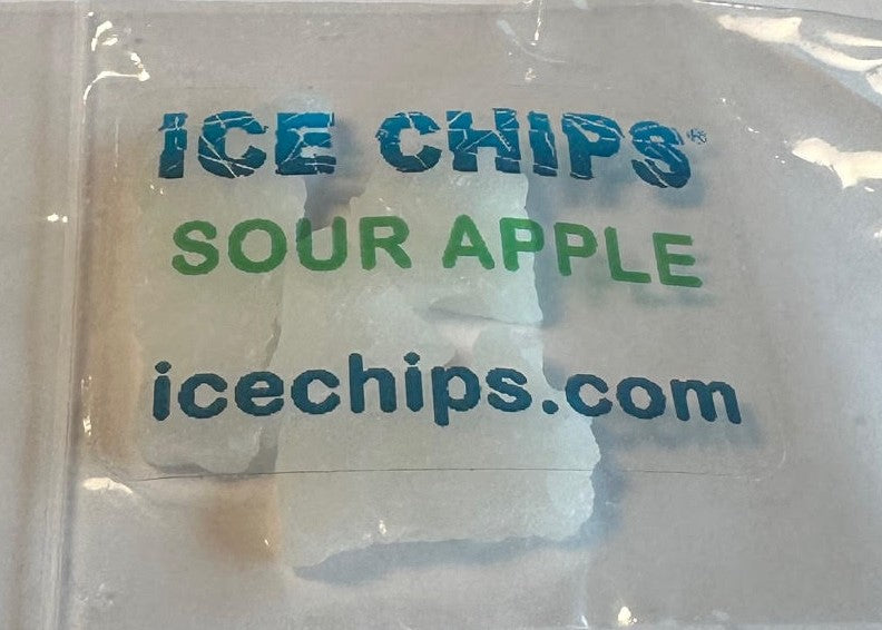 A clear plastic bag containing ice chips, with a printed label reading 'ICE CHIPS SOUR APPLE' and 'icechips.com' in blue and green text.