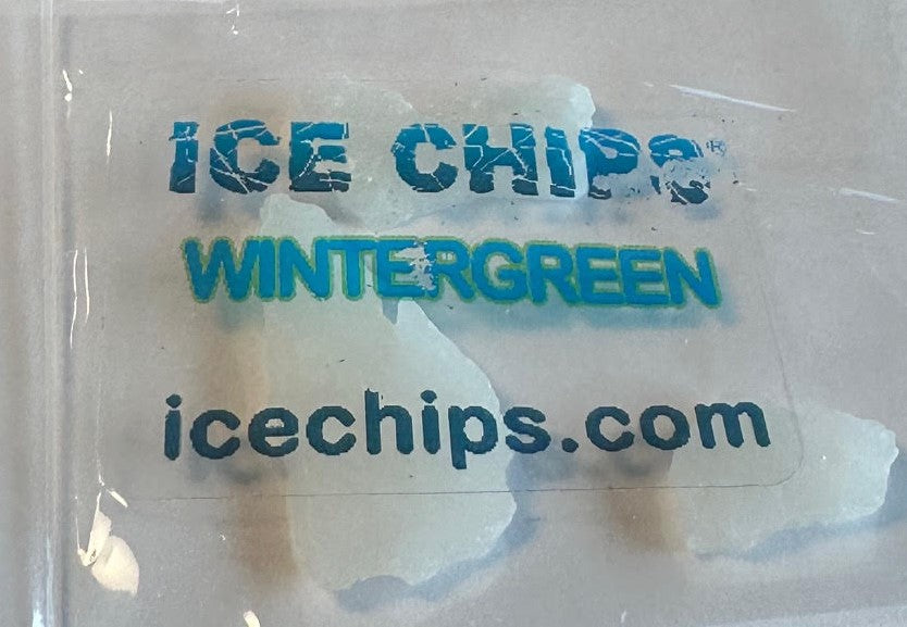 A close-up of a clear plastic bag containing ice chips, with blue printed text reading 'ICE CHIPS', 'WINTERGREEN', and 'icechips.com' on the front.
