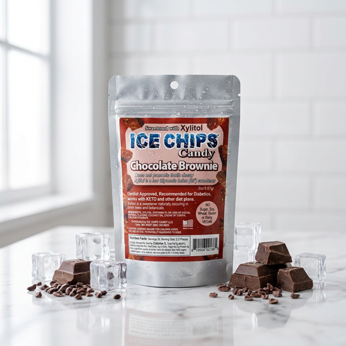 A stand-up pouch of Ice Chips Candy Chocolate Brownie ice chips sits on a white marble surface with scattered chocolate pieces and clear ice cubes. The package is centered against a bright white tiled kitchen-style background.