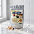 A stand-up pouch of Ice Chips Candy Egg Nog flavor sits on a white marble surface with ice cubes, a cinnamon stick, and scattered cocoa powder. The pouch is centered against a bright, softly blurred kitchen or studio background.