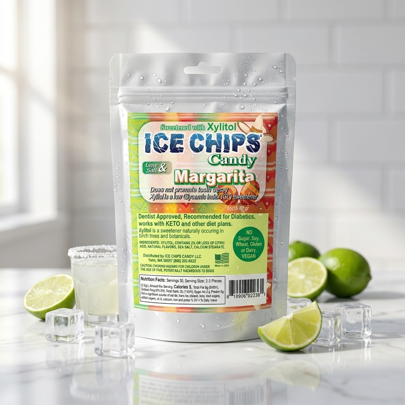 A stand-up pouch of Ice Chips Candy Margarita flavored Xylitol Candy, surrounded by lime slices, ice cubes, and a margarita glass on a marble surface with a white tiled background.