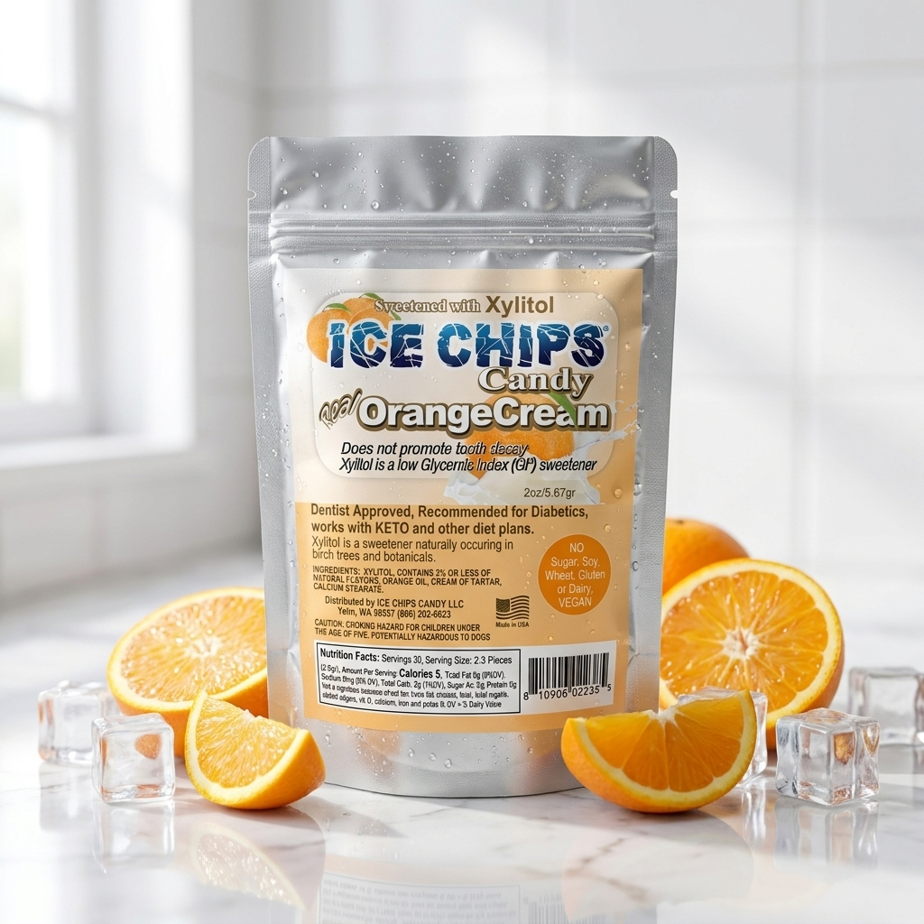 A stand-up pouch of Xylitol Ice Chips Candy in Orange Cream flavor, styled on a white marble surface with sliced oranges and ice cubes. The background is a bright, softly blurred kitchen setting.