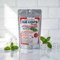 A stand-up pouch of Ice Chips Candy  Peppermint flavored Xylitol Candy, styled on a white reflective surface with mint leaves and clear ice cubes against a white tiled background.