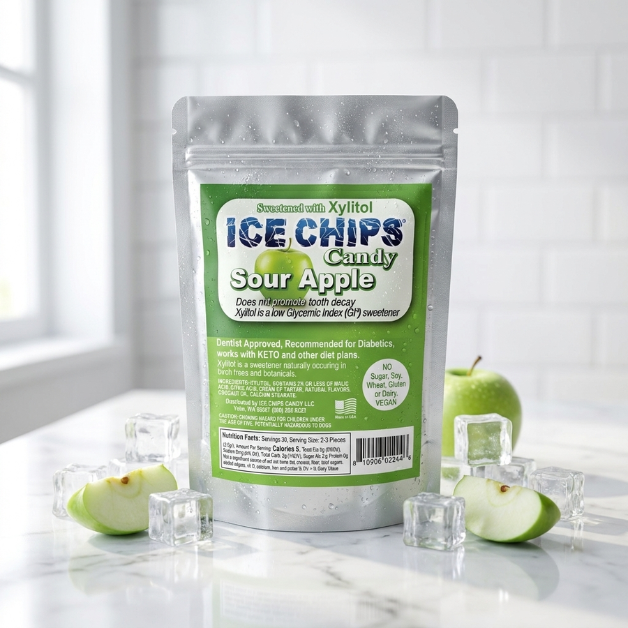 A stand-up pouch of Ice Chips Candy Sour Apple Candy sits on a white marble surface with ice cubes and sliced green apples around it. The pouch has a silver body with a large green front label.
