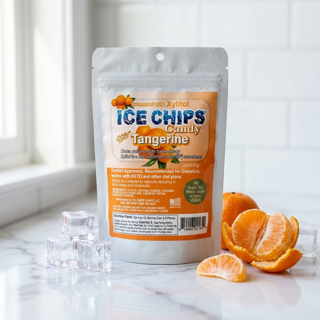 A stand-up pouch of Ice Chips Candy Tangerine candy sits on a marble surface with orange slices and a few clear ice cubes around it. The package is white with a large orange label and blue branding text.